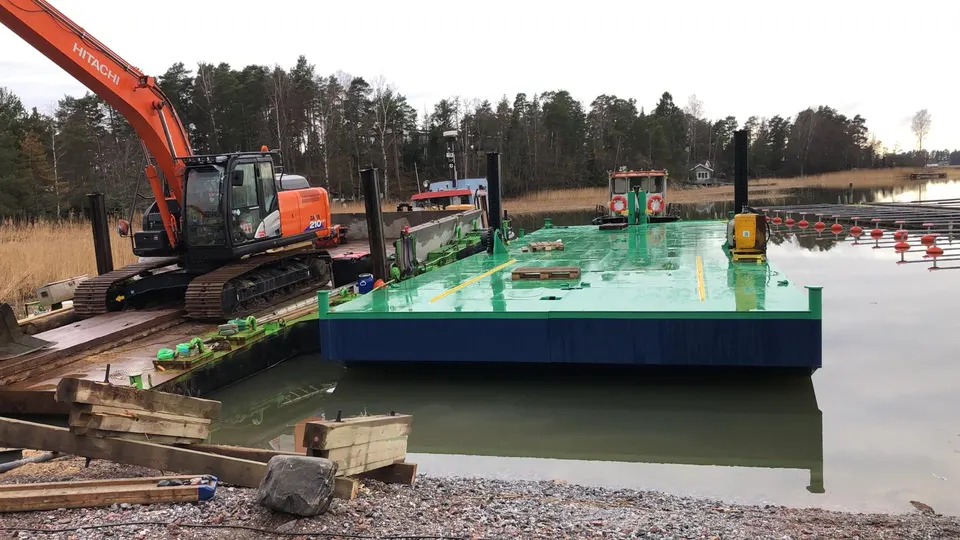 Large flat-top steel platform fitted out at dock with Hitachi excavator